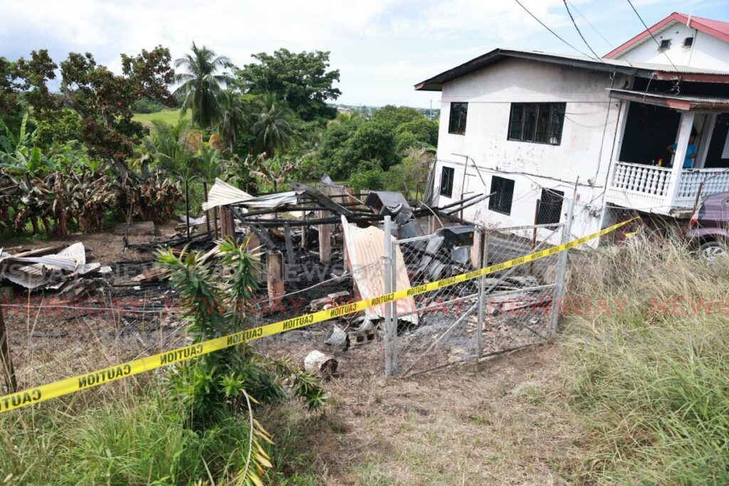 The remains of a house burnt down by its owner at Dow Village, South Oropouche, on Sunday. The house next to it was also damaged by the fire. - Jeff K. Mayers