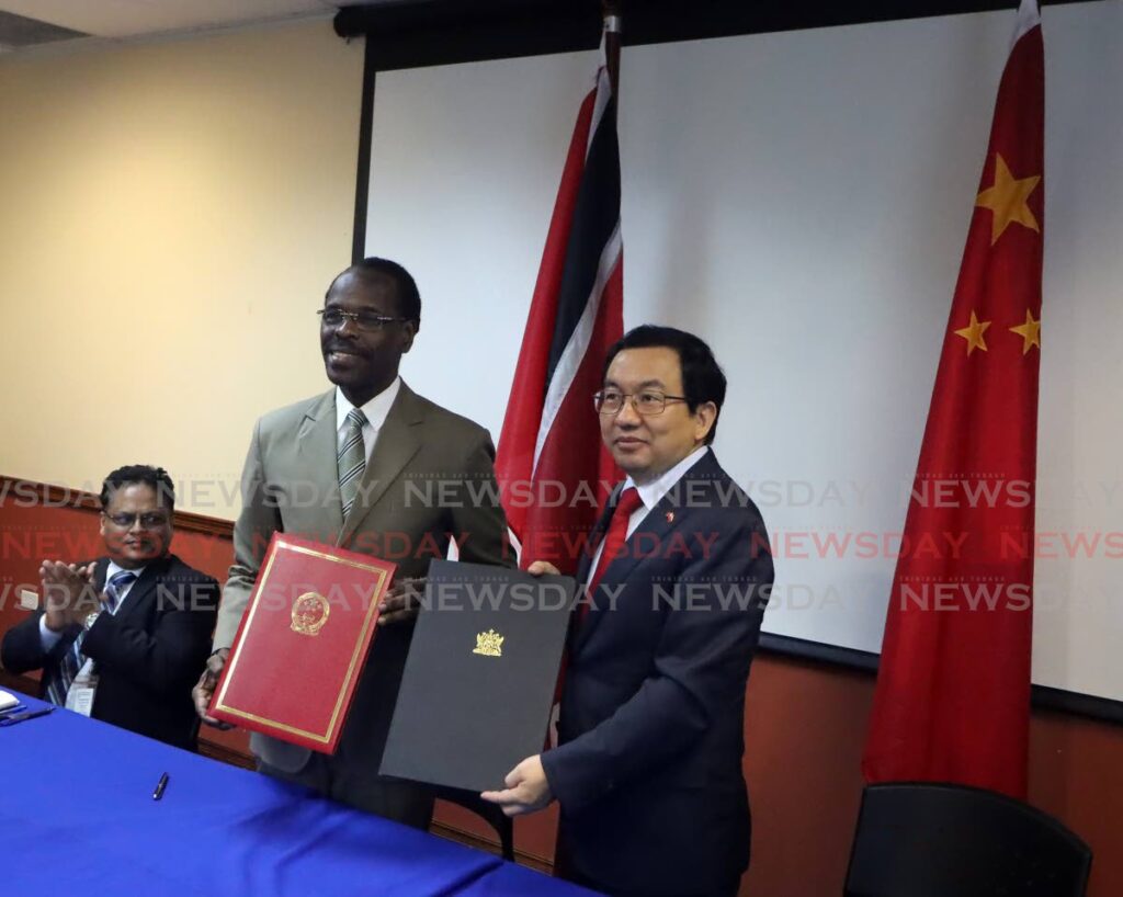 National Security Minister Fitzgerald Hinds, second from left, and Chinese Ambassador to Trinidad and Tobago Fang Qiu engage media after signing a memorandum of understanding for the funding and building of a new forensics science centre at Farm Road, St Joseph, at a signing ceremony at the International Waterfront Complex, Port of Spain, on Monday. - Photo by Roger Jacob