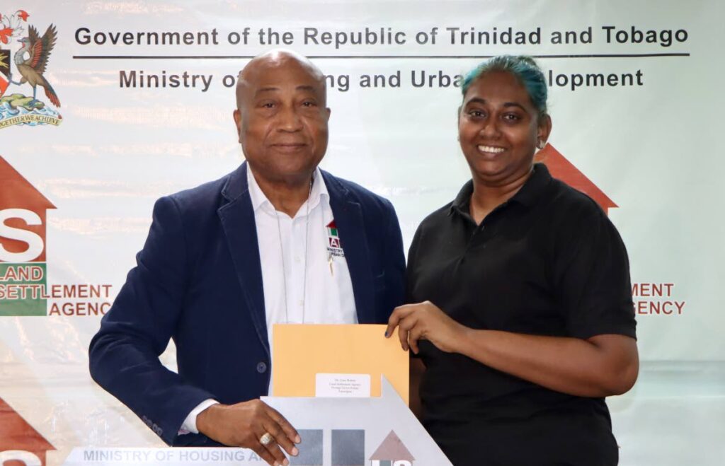 LSA chairman Wayne Innis presents a package to Lisa Mohan who was one of 37 people receiving keys to new homes on Tuesday at the LSA’s Tacarigua office.
 - Photo by Angelo Marcelle