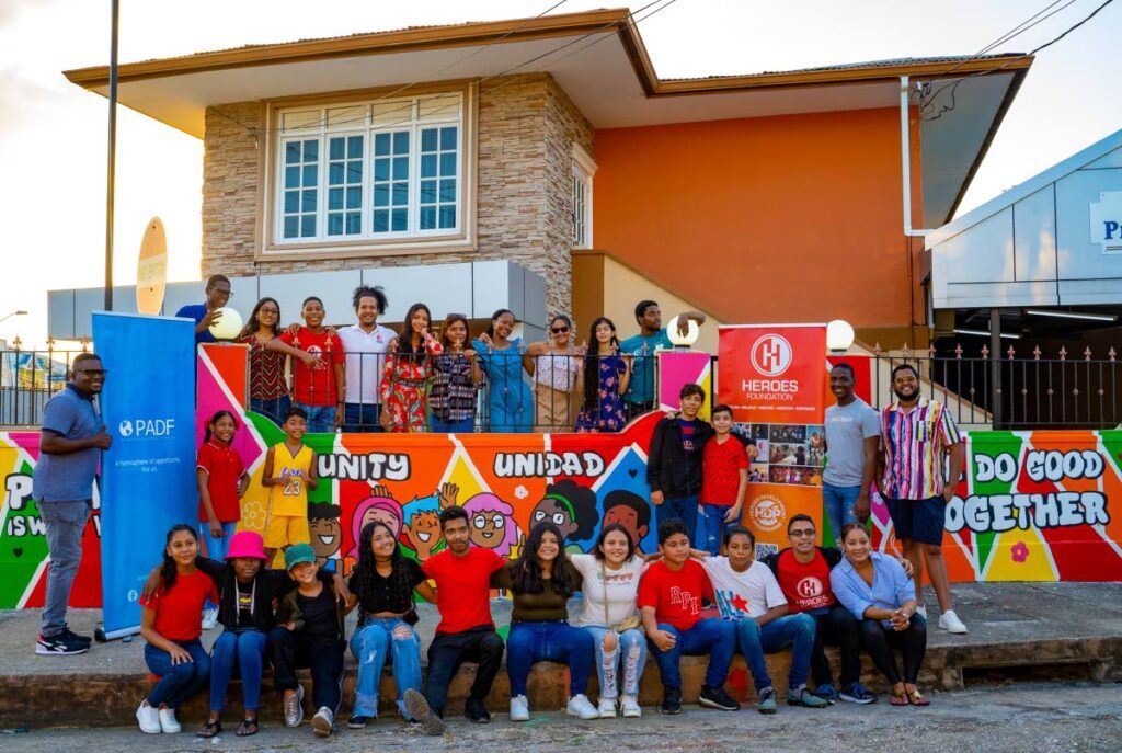 Local and migrant participants in the Heroes Development Programme proudly pose with their Peace and Unity Mural at the Heroes Headquarters in Woodbrook. - 