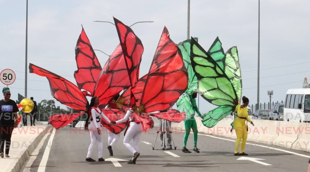 Performers in butterfly costumes dance along the Westmoorings interchange in Diego Martin after its commissioning on Friday. - Photo by Roger Jacob