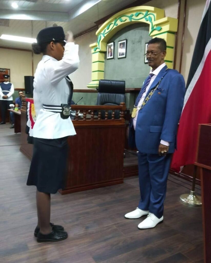 A police officer salutes chairman of the Penal/Debe Regional Corporation Diptee Ramnath after he was sworn into office in August. Ramnath died on Friday.  - 
