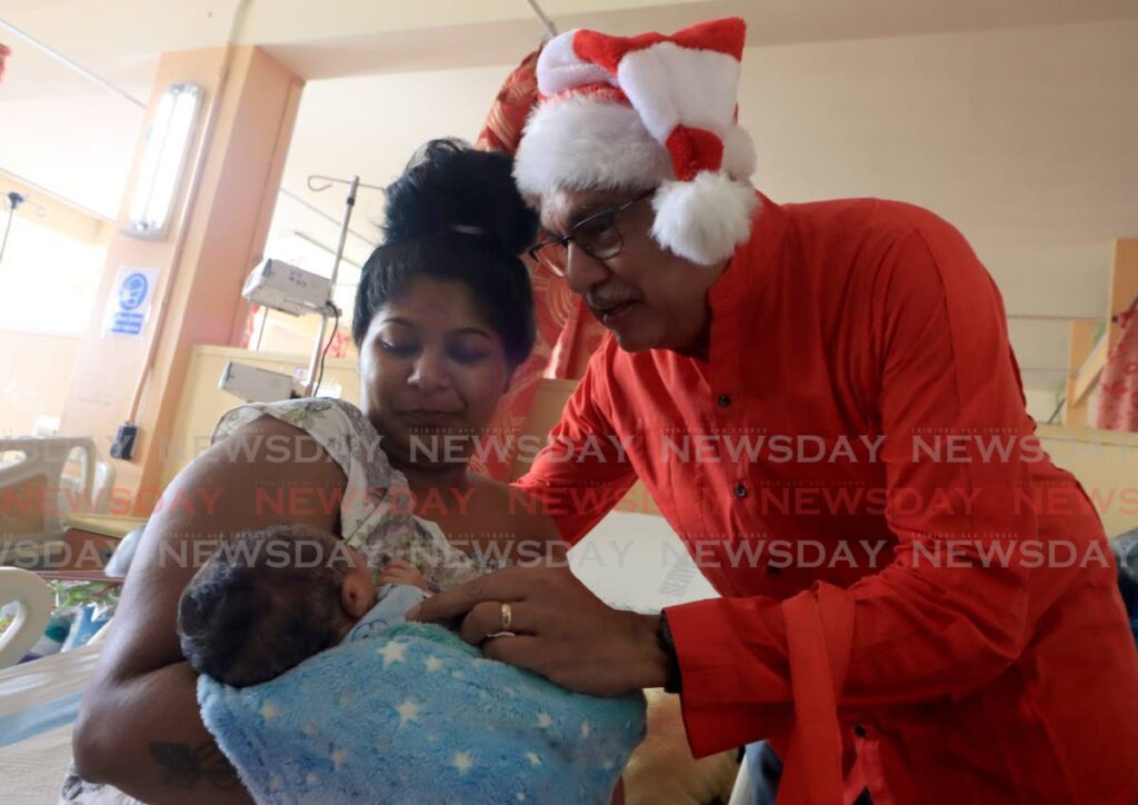 Health Minister Terrence Deyalsingh interacts with Malini Singh's newborn during his interaction with Christmas Day mothers and their babies on Monday. - Photo by Roger Jacob