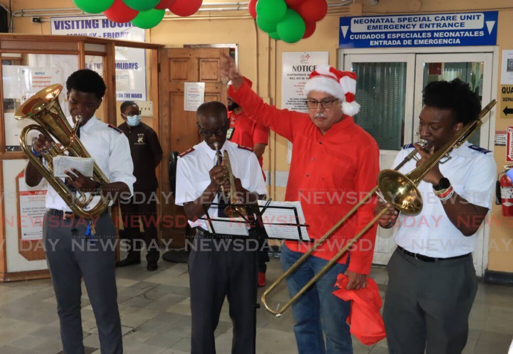 Health Minister Terrence Deyalsingh helps spread Christmas cheer with the Salvation Army's music band during his visit to mothers who gave birth on Christmas Day at the Mt Hope Women's Hospital on Monday. - Photo by Roger Jacob