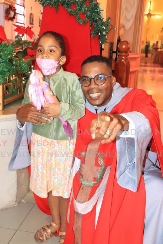 Fr Jayson Grell with little Ariya Ali, four, during the feast of Holy 
Innocents at Our Lady of Perpetual Help Church, San Fernando on Thursday. Photo by Roger Jacob