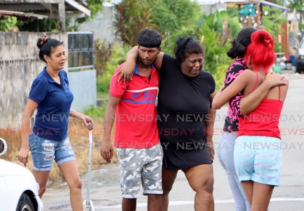 Relatives of Anand Bisson and Shane Ramjitsingh console each other at Benny Lane, Dookiesingh Extension, St Augustine on Saturday. - Angelo Marcelle