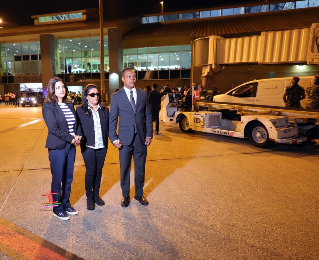 Amery's Support: Foreign and Caricom Affairs Minister Dr Amery Browne holds hands with a weeping Oma Panday who is also supported by daughter Mickela as the body of former prime minister, Basdeo Panday, arrived on Wednesday at Piarco International Airport  - Photo courtesy the Government Information Division