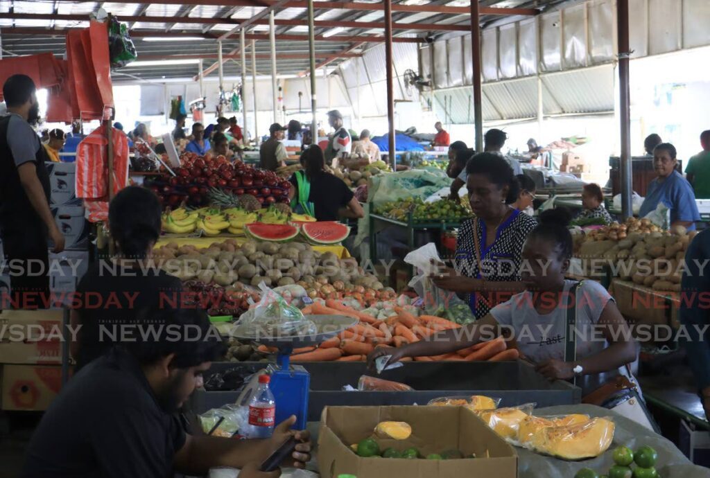 BUYING AND SELLING: Vendors and customers interact at the Tunapuna market on Thursday, hours after a shooting incident outside the market on Wednesday night, left two men dead and three others wounded. Photo by Roger Jacob