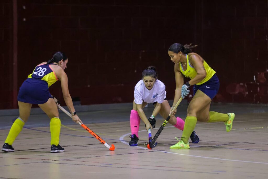 Magnolia’s Savannah De Freitas (R) vies for possession with GBTI GCC’s Madison Fernandes (C) during the Ventures Indoor Hockey International Invitational Tournament women's match at the Woodbrook Youth Facility on Friday in Port of Spain.   - DANIEL PRENTICE