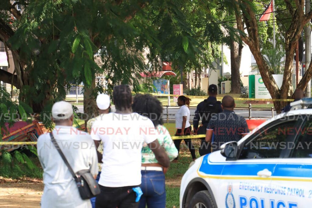 Relatives of Akil Archer look on as police process the scene of his murder at the Queen's Park Savannah, Port of Spain, on Sunday. - ROGER JACOB