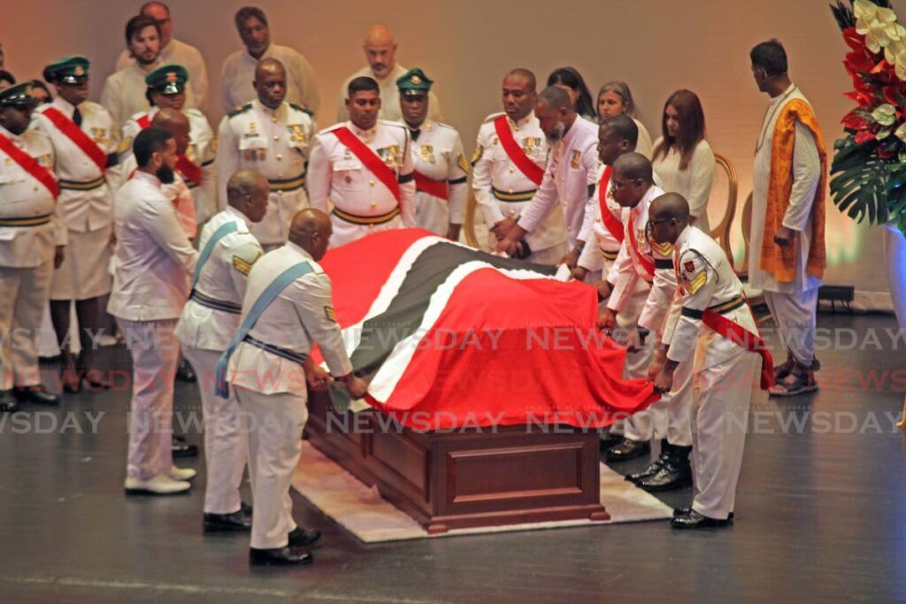 Military personnel drape the casket of Basdeo Panday with the national flag during Tuesday's state funeral for the former prime minister at the Southern Academy for the Performing Arts, San Fernando. PHOTO BY LINCOLN HOLDER - 