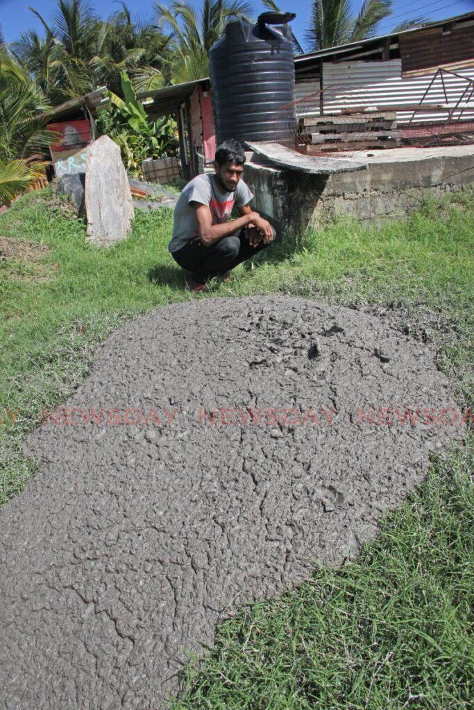 ERUPTION: Rakesh Seecheran stoops by the dried mud which is located walking distance from his home after a new mud volcano formed and erupted in Cascadoux Trace, Mayaro on Thursday. He and his family have since been evacuated. - Photo by Lincoln Holder 