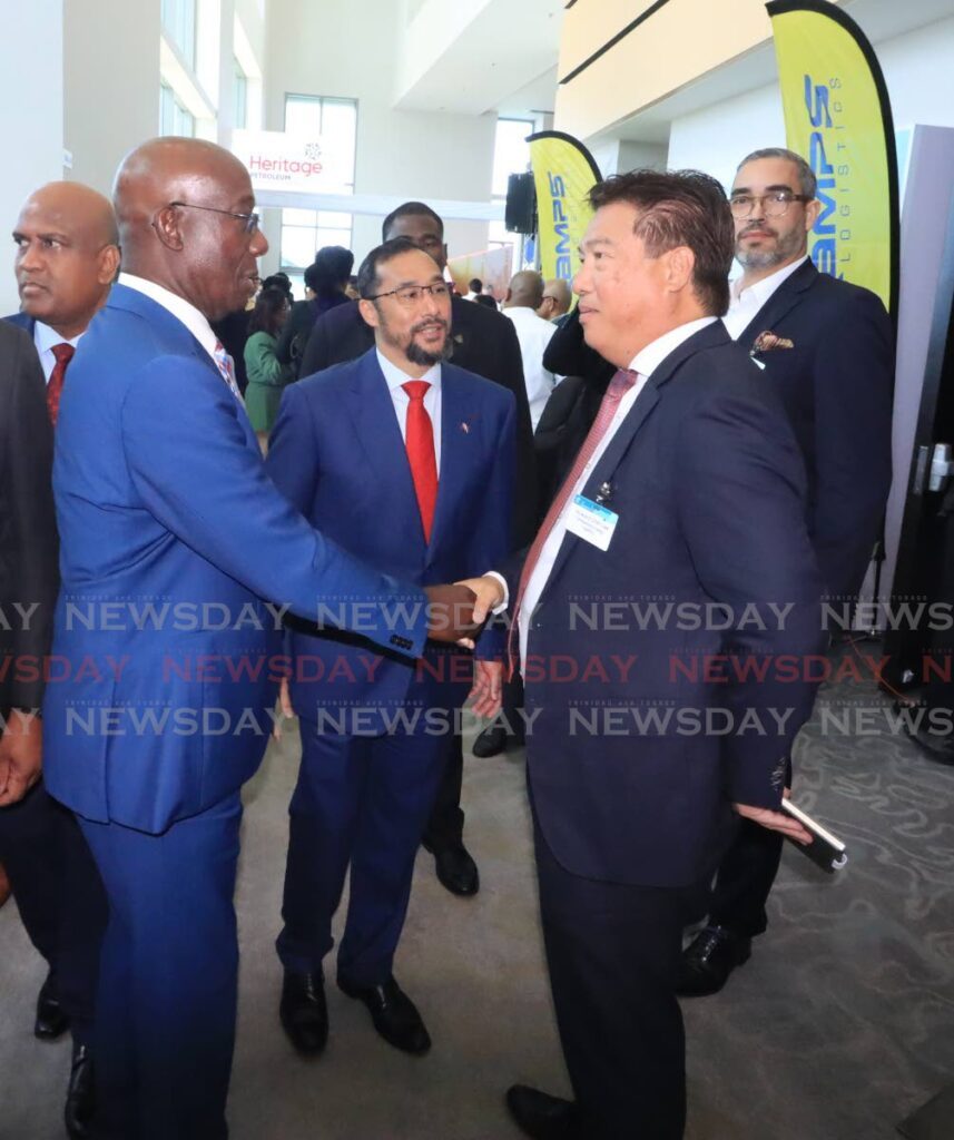Prime Minister Dr Keith Rowley greets former national security minister Howard Chin Lee at the Energy Conference at the Hyatt Regency in Port of Spain. At centre is Energy Minister Stuart Young. - Photo by Roger Jacob