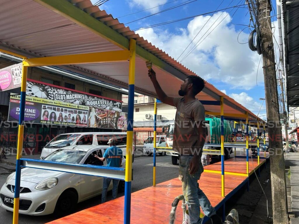 City corporation worker Nicholas Surujlal paints the new vendors' stalls on Mucurapo Street, San Fernando on Thursday. - Photo by Rishard Khan
