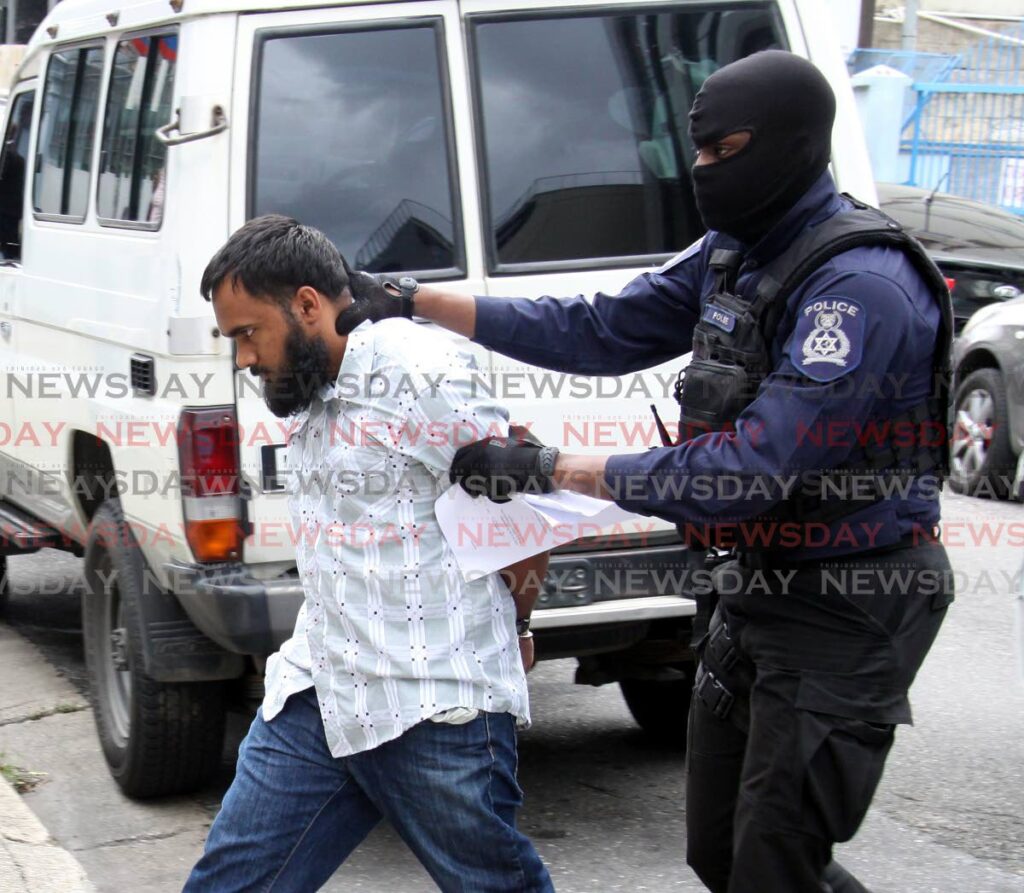 Jonathan Mohammed is escorted by police to the Port of Spain Magistrates' Court. - File photo by Angelo Marcelle