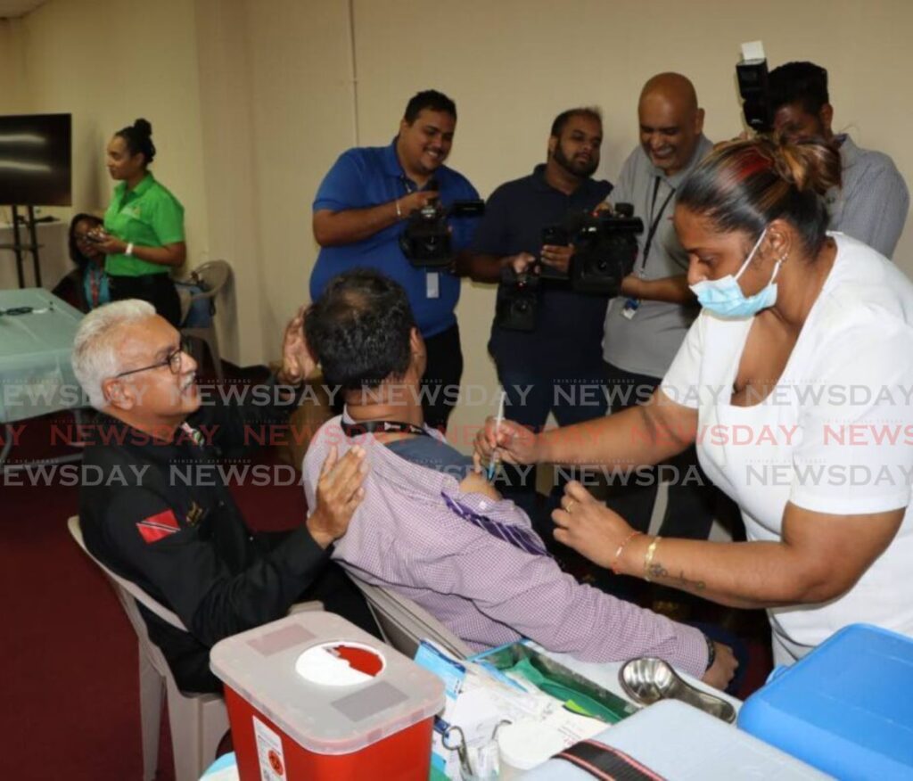 Health Minister Terrence Deyalsingh, left, looks on as a member of the media takes his influenza shot at the Divali Nagar, Chaguanas on Monday.  - Photo by Angelo Marcelle