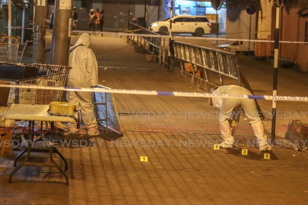 Crime scene unit investigators gather evidence at the Tunapuna Market after a shooting incident which left two people dead and three others injured on January 3.  - Jeff Mayers