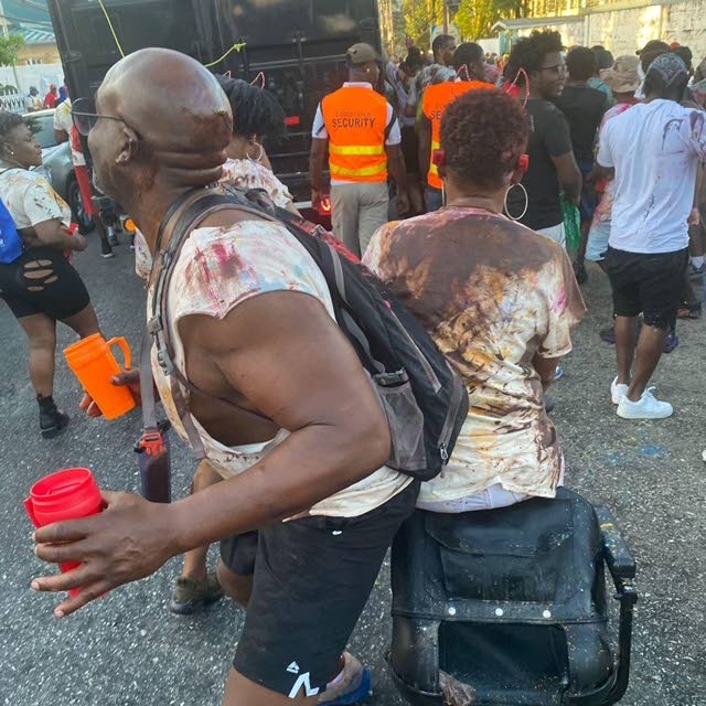 Stacey Samuel-O'Brien, right with back turned to camera, gets into the J'Ouvert jam with a reveller. - 