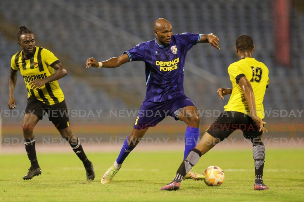 Defence Force FC’s Brent Sam, centre, tries to maintain 
possession against Central FC’s Levin Caballero during the TT Premier Football League match at the Hasely Crawford Stadium, Port of Spain on January 26. - File photo by Daniel Prentice