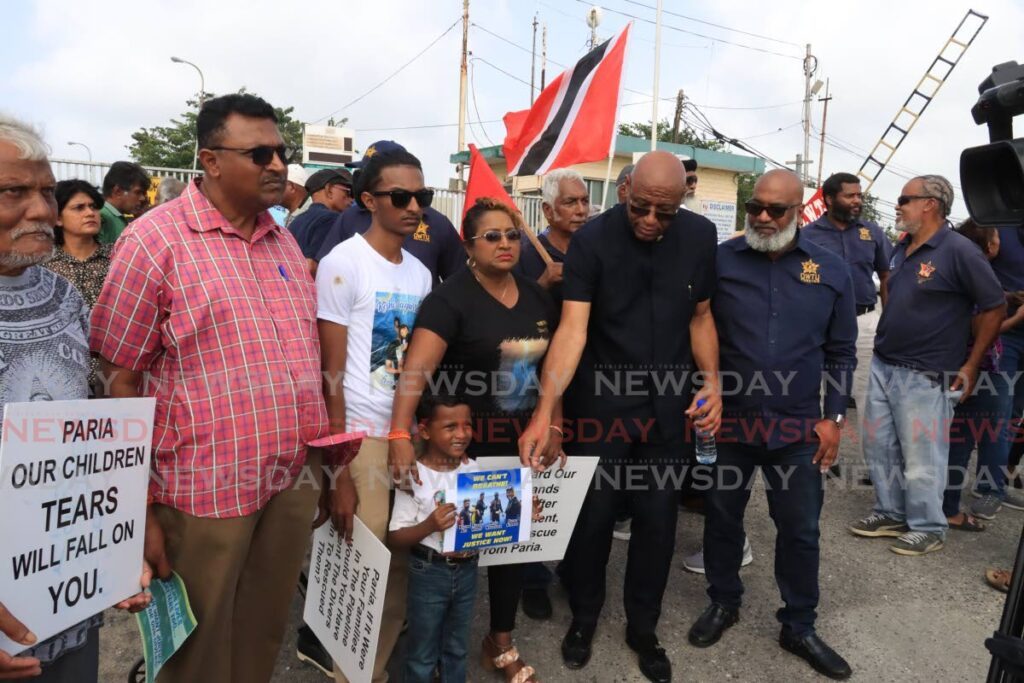 OWTU president general Ancel Roget reaches out to little Nashik Nagassar, four, during a protest at the Pointe-a-Pierre roundabout on February 1. Nashik's father Rishi was one of four divers who drowned in the Paria incident in 2022. - Photo by Roger Jacob