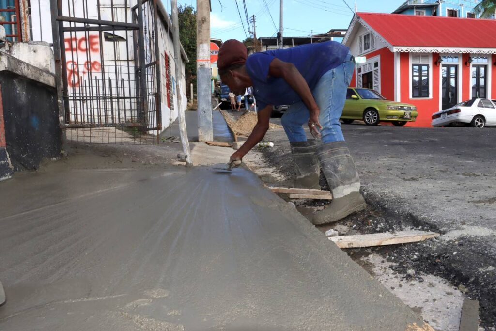 A labourer smoothens the freshly laid cement for pavement works on Piccadilly Street in East Port of Spain. - File photo by Roger Jacob