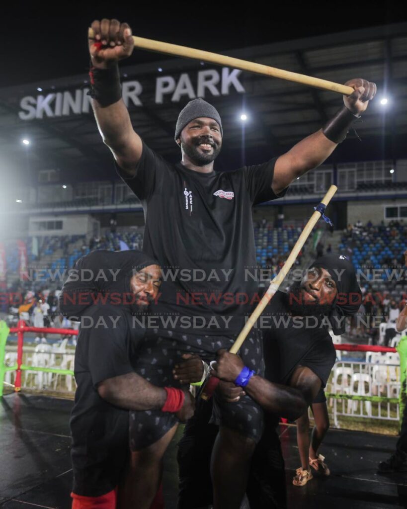Stickfighting winner Oneil Odle, lifted in celebration by Ronald and Donald Lewis during the National Carnival Commission Stickfighting Finals at Skinner Park on February 7. - Photo by Daniel Prentice
