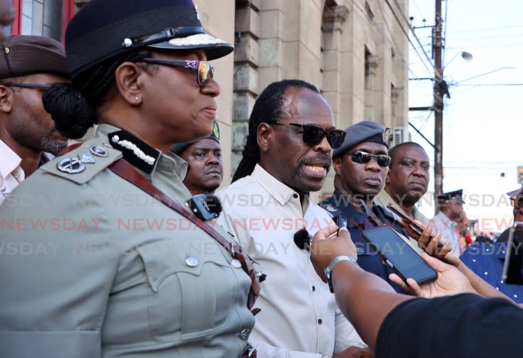 Minister of National Security Fitzgerald Hinds, second from left, speaks with the media during the walk about at South Quay, Port of Spain. - Photo by Ayanna Kinsale