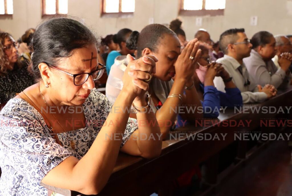 DIVINE BLESSING: Worshippers kneel as they pray during the Ash Wednesday mas at Sacred Heart RC church in Port of Spain on February 14. - Photo by Ayanna Kinsale