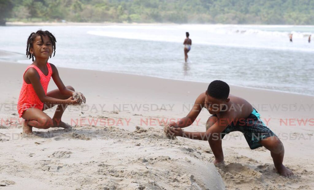 Zamora and Elyk Stafford, 5 and 9 respectively, play in the sand at Maracas Beach.