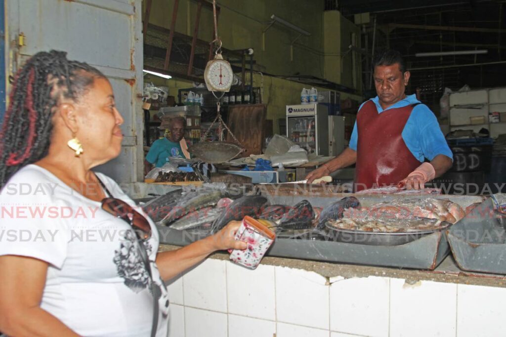 Lucia Hazzard buys fish from Balram's Something Fishy on George Street, Port of Spain on February 15. - Faith Ayoung