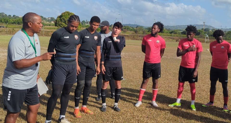 TT men's under-20 football team coach Brian Haynes, left, speaks to his young charges during a training session on Thursday. - Photo courtesy TTFA media.  