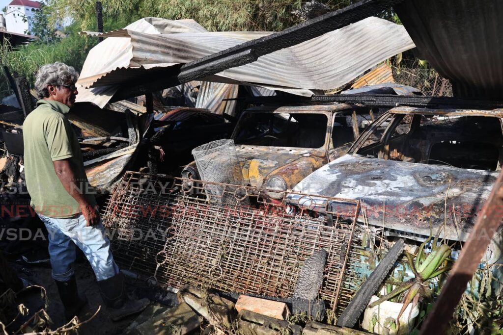 A homeowner who only identified himself as Sarawan stands next to several burnt 'antique' vehicles after a bushfire at the back of his home on Bonanza Street in Princes Town spread to his property causing damage on February 21. Firefighters were able to stop the blaze before it damaged his home. - Photo by Lincoln Holder 