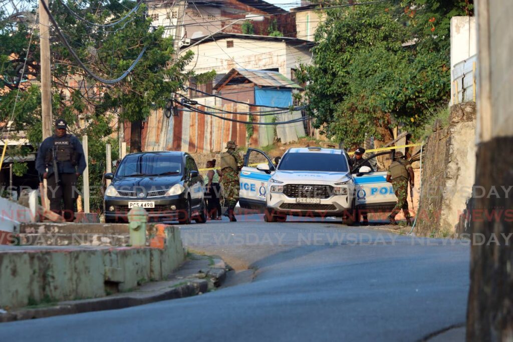 Police and army officers secure the scene where Ezekiel Paria, 11, was shot dead during a drive-by at Laventille Road, East Dry River, Port of Spain, on February 22.  - Photo by Angelo Marcelle