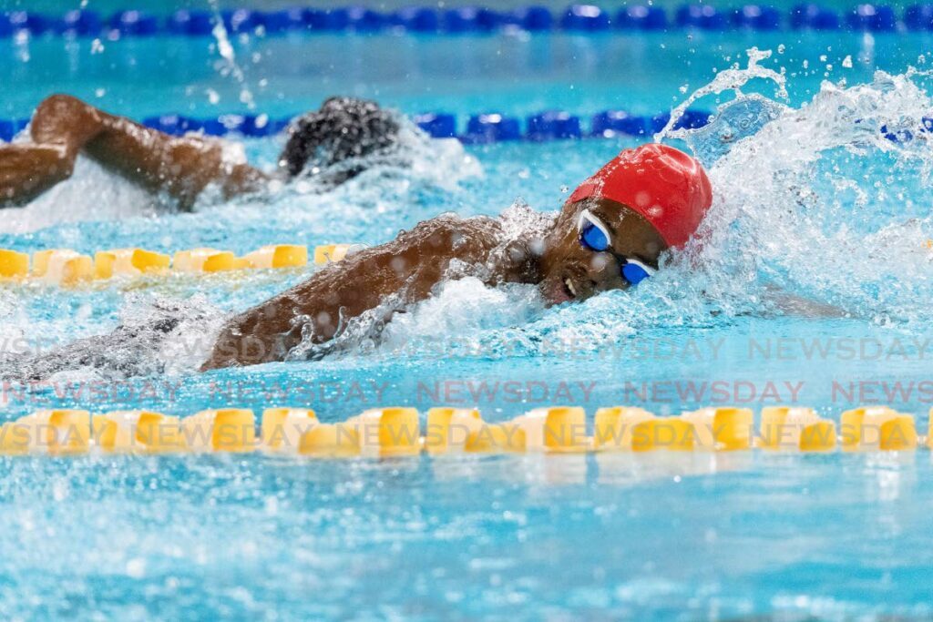 Jonathan Sambrano of Flying Fish, right, splashes to a lead time of 57.22 in heat 4 of the Boys 13-14 100m freestyle prelims at the National Long Course Age Group Championships on Thursday night at the National Aquatics Centre, Couva.  - Photo by Dennis Allen for @TTGameplan