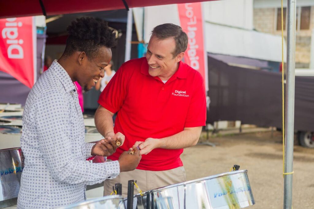 CEO of Digicel Trinidad and Tobago and board director of the Digicel Foundation Abraham Smith (on the right), gets a quick pan lesson at Pandemonium Panyard in Belmont at the launch of the Digicel Foundation’s Technology in Education Centres on  February 28.  - Photo courtesy Digicel Foundation
