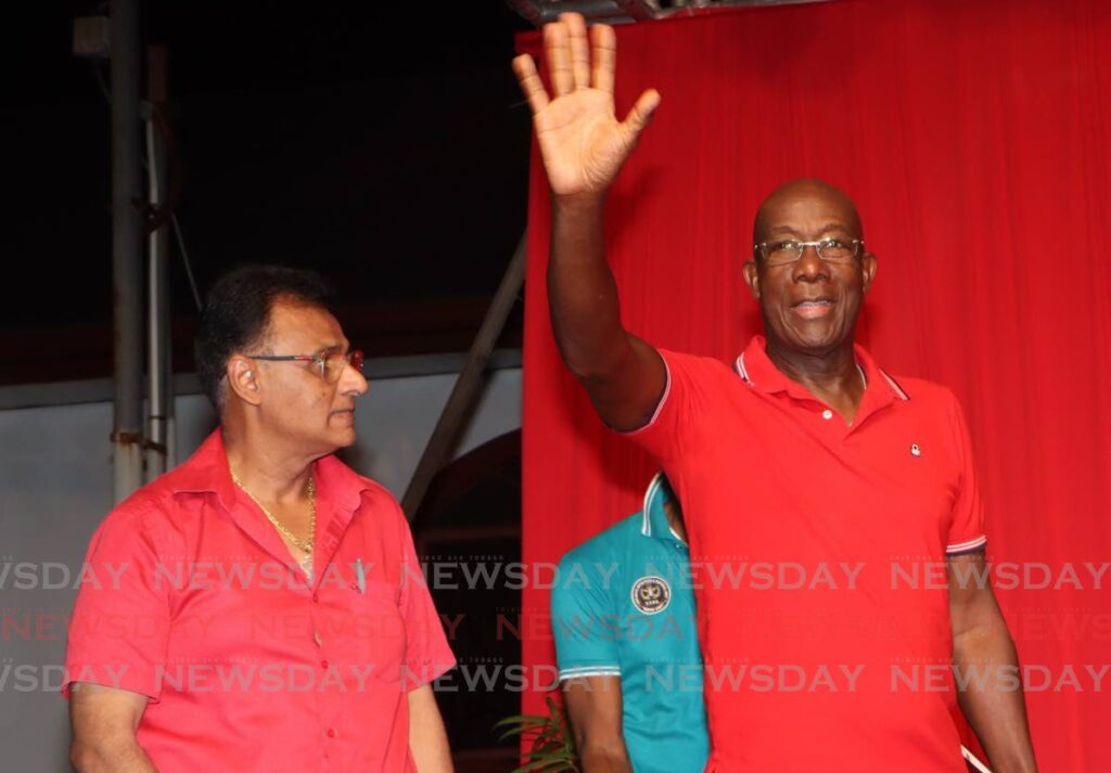 Prime Minister Dr Keith Rowley waves to supporters at a PNM political meeting at Tropical Angel Harps Pan Yard, Chaguanas, on March 7, as Works and Transport Minister Rohan Sinanan looks on. - Photo by Angelo Marcelle