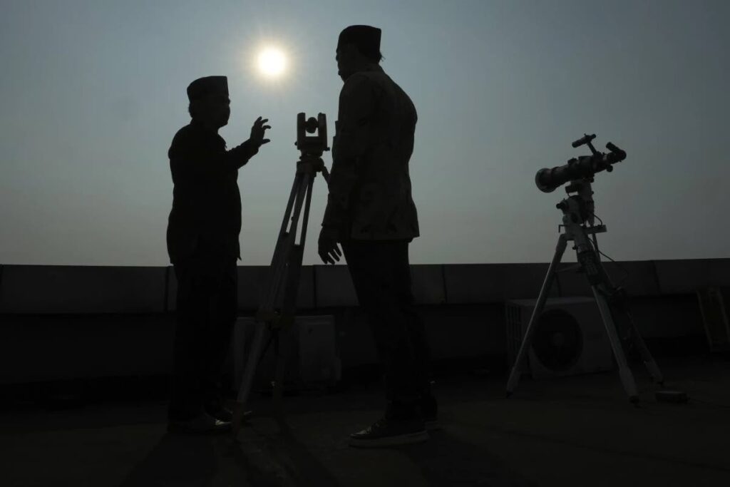 FILE: Officials are silhoutted as they use a telescope to scan the horizon for a crescent moon that will determine the beginning of he holy fasting month of Ramadan in Jakarta, Indonesia on March 22, 2023.  - AP Photo