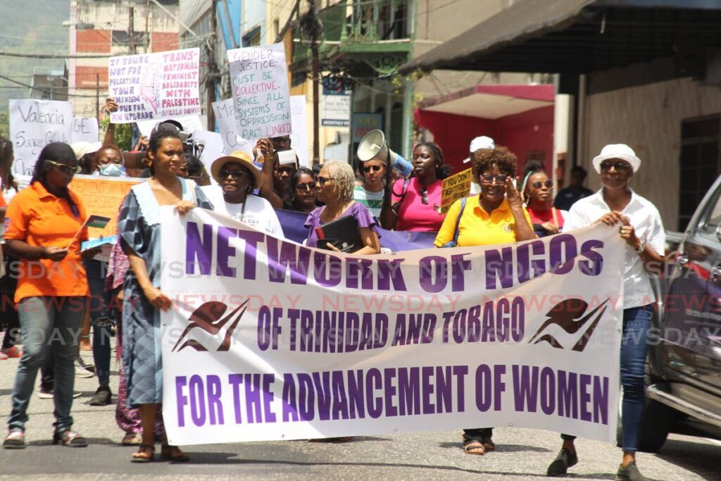 Women, men and youths hold placards, chant slogans and invite members of the public to join the women’s rights march around Woodford Square, Port of Spain, for International Women’s Day on March 8. - Photo by Faith Ayoung