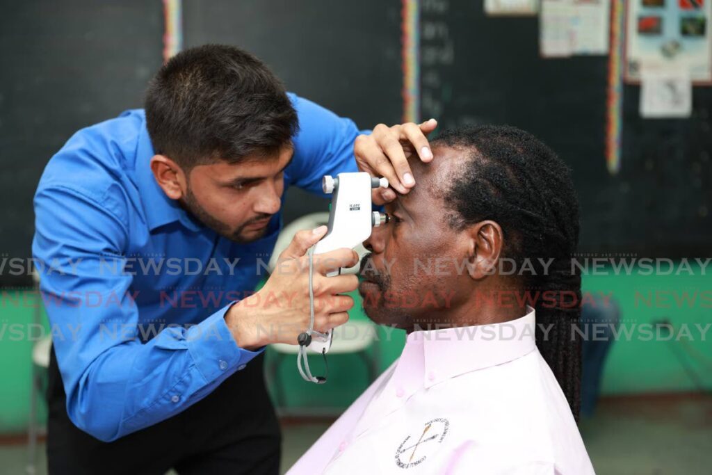 National Security Minister and Laventille West MP Fitzgerald Hinds gets his eye pressure tested by Trinidad Eye Hospital's Kyle Christo at the Excell Beetham Government Primary School on March 10. - Photo by Jeff K. Mayers 