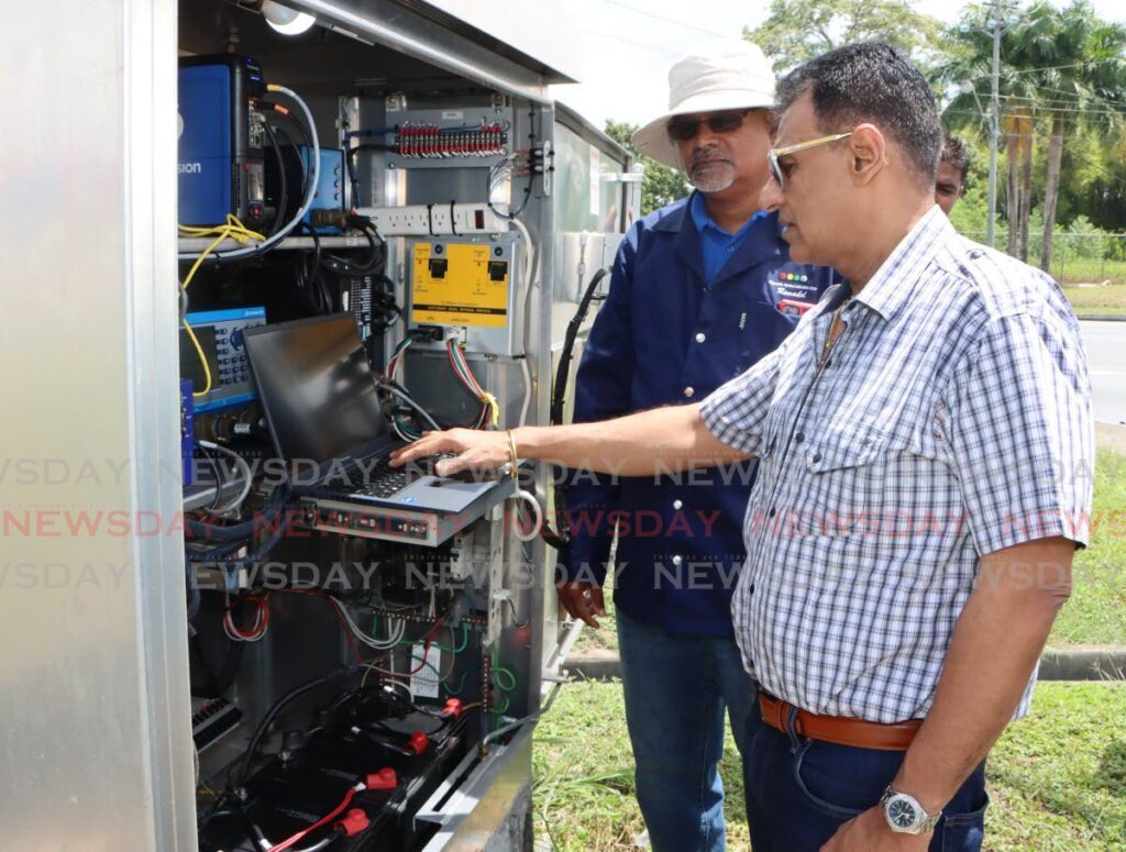Works and Transport Minister Rohan Sinanan examines the newly installed Traffic Signal Detection equipment at the corner of the Churchill Roosevelt highway and Golden Grove Road, Piarco on March 17.  Looking on is signal specialist Ronald Rackal. - Photo by Angelo Marcelle
