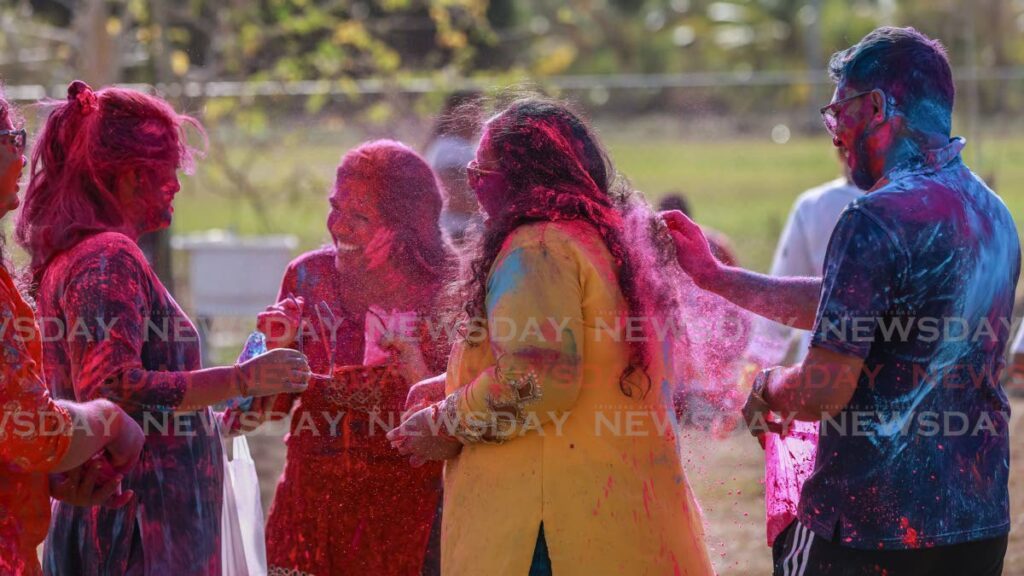 A group of friends cover each other in coloured powder as they enjoy Phagwa celebrations at the Hindu Prachaar Kendra Temple in Chaguanas on March 24. - Photo by Jeff K. Mayers