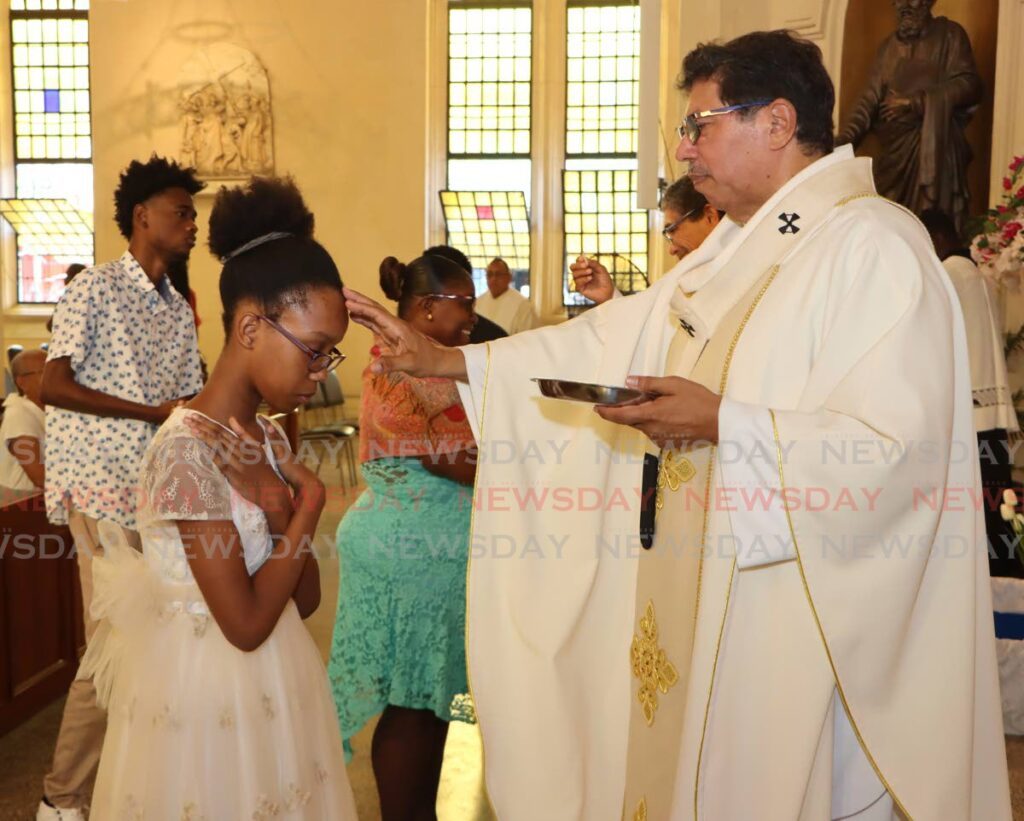 Archbishop Jason Gordon prays for a young parishioner during Easter Sunday mass at the Cathedral of the Immaculate Conception, Port of Spain, on March 31. - Photo by Angelo Marcelle