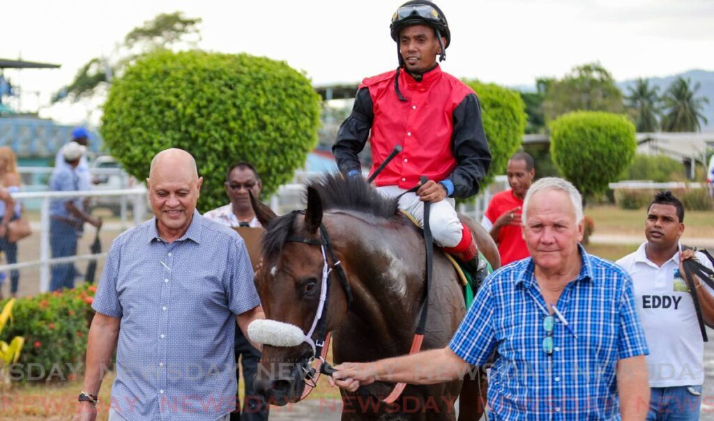 Hello World, ridden by Brian Boodramsingh, gets escorted to the winner's circle by owner Neil Poon Tip, left, and trainer John O’Brien, right, after winning the Arima Race Club Dixee Crackers Champagne Stakes at the Santa Rosa Park on March 30, in Arima.  - Photo by Daniel Prentice