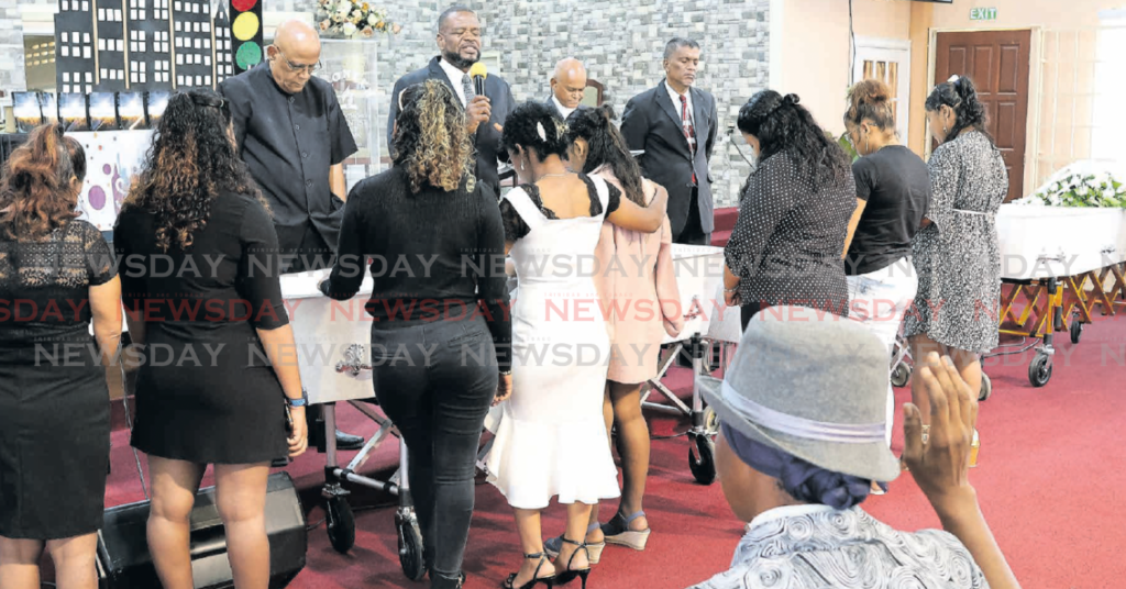 Family members say farewell to three of four men murdered in Bristol Village, Mayaro, last week: Buddy George, Marcus Buddy and Jeremiah George,
at their funeral at Pioneer Seventh Days Adventist Church, Couva, on March 20. - Photo by Lincoln Holder