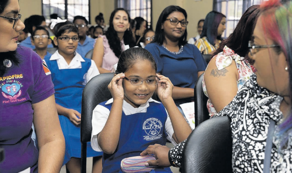 A pupil of the Brothers Presbyterian School tries on her glasses as her mother looks on at the Williamsville Community Centre.