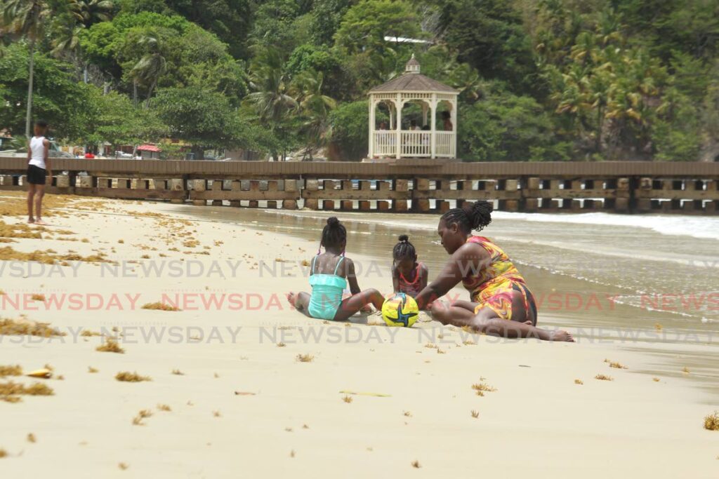 As part of an Easter family trip, Arlene plays in the sand with 5 year old twins, Rian and Riana Williams at Maracas beach on Easter Monday. - Photo by Faith Ayoung