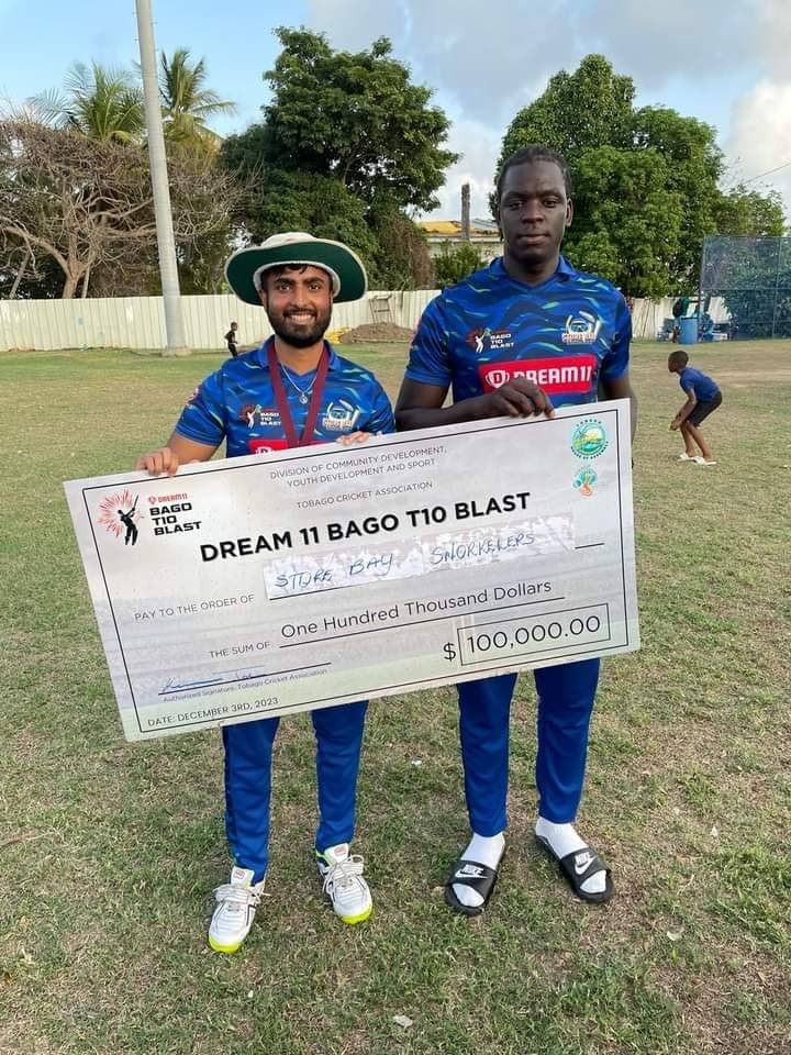Store Bay Snorkelers Joshua James, right, and Govinda Ramlogan celebrate with the winner's cheque after their team won the Dream11 Bago T10 Blast at Shaw Park Recreation Ground on Friday.  - 