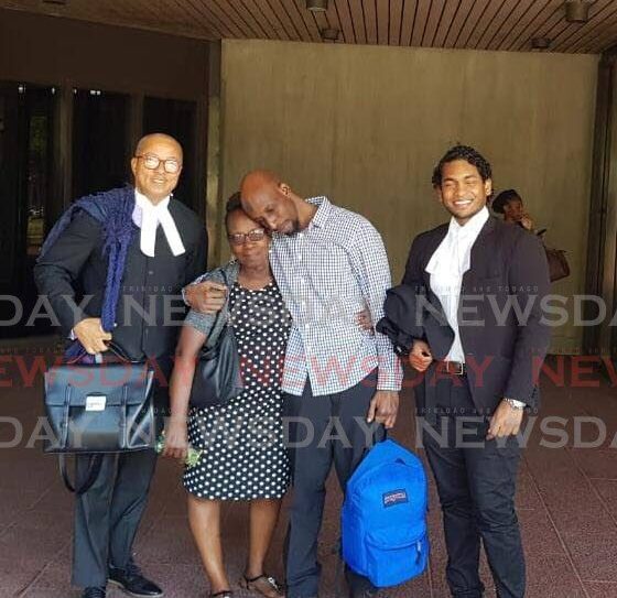 Linden Roberts, in the company of his attorneys Larry Williams (left) and Shawn Morris, embraces his mother at the Hall of Justice, Port of Spain, on April 9 after he was freed of a 2009 murder. - Photo by Jada Loutoo