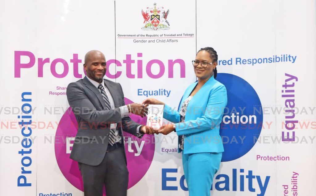 General manager of the TT Postal Corporation Marcus McLeod recieves a brochure from the Minister of Gender and Child Affairs Ayanna Webster-Roy at the Office of The Prime Minister, St Clair on April 12. - Photo by Venessa Mohammed