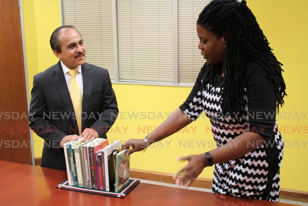 Mexican ambassador Victor Hugo Morales delivers a collection of books from his country translated into English to NALIS executive director Paula Greene as part of the commemoration of World Book Day on April 23. - Photo by Grevic Alvarado